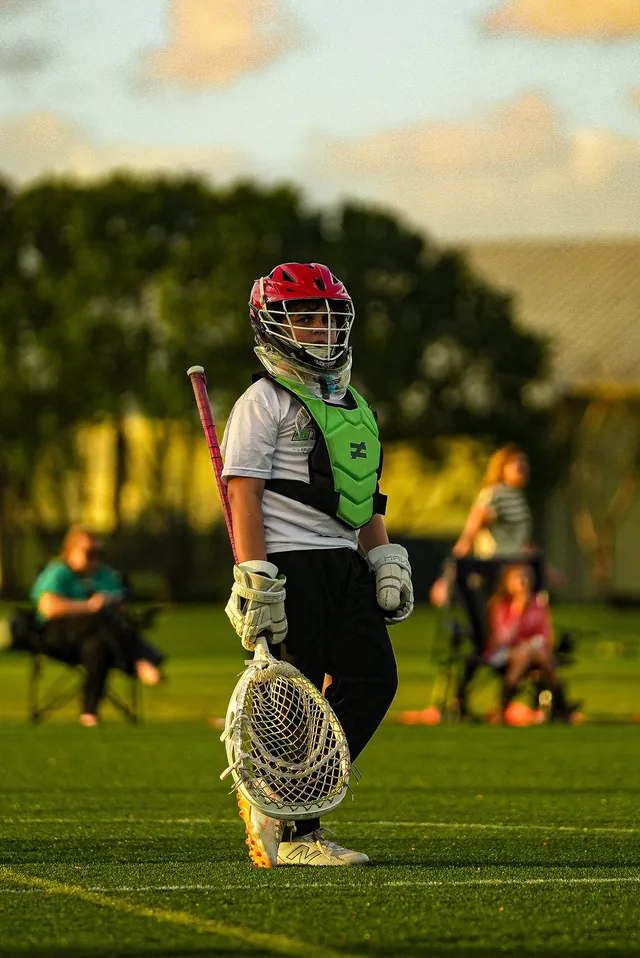 A Redhawks goalie in a red helmet stands ready beside the goal